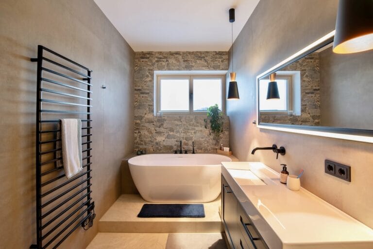 Badezimmer mit freistehender Badewanne vor Wand in Steinoptik